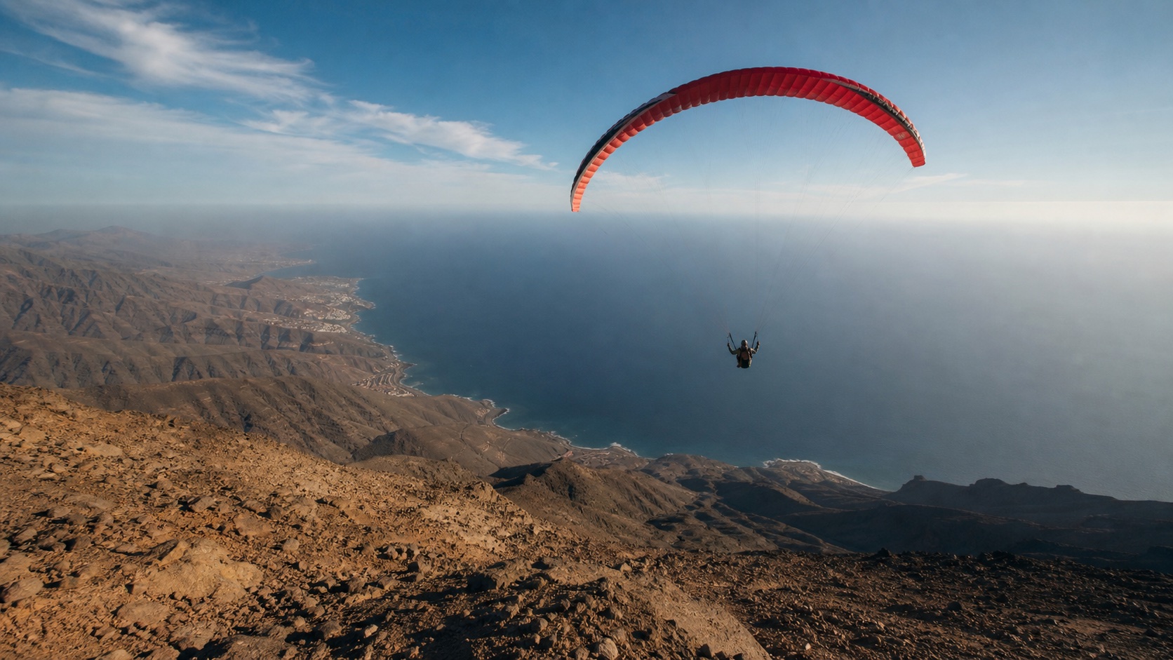 Un parapente queda suspendido sobre la costa volcánica de Tenerife