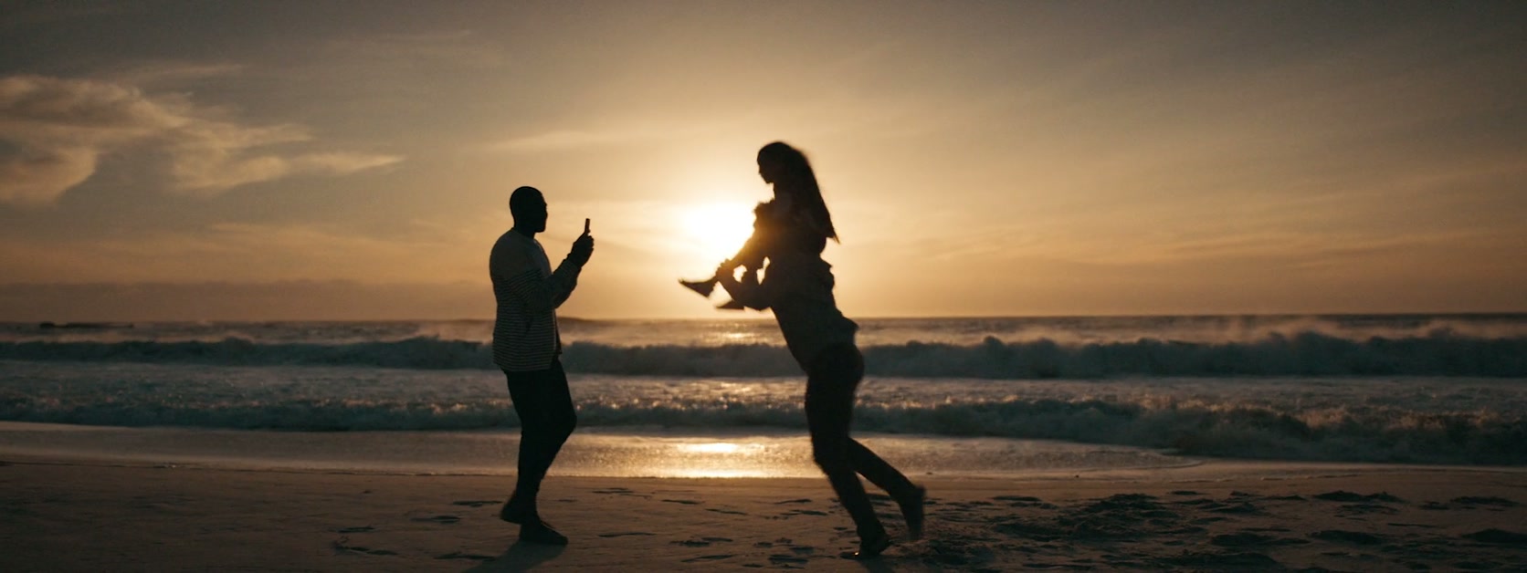 Dos personas juegan y bailan junto al mar