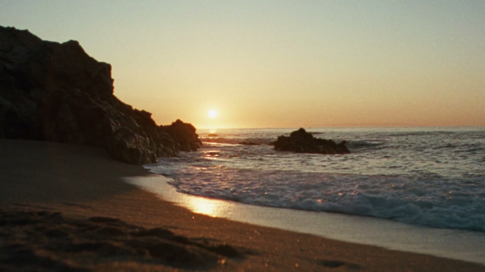 El sol se pone sobre una playa de arena oscura