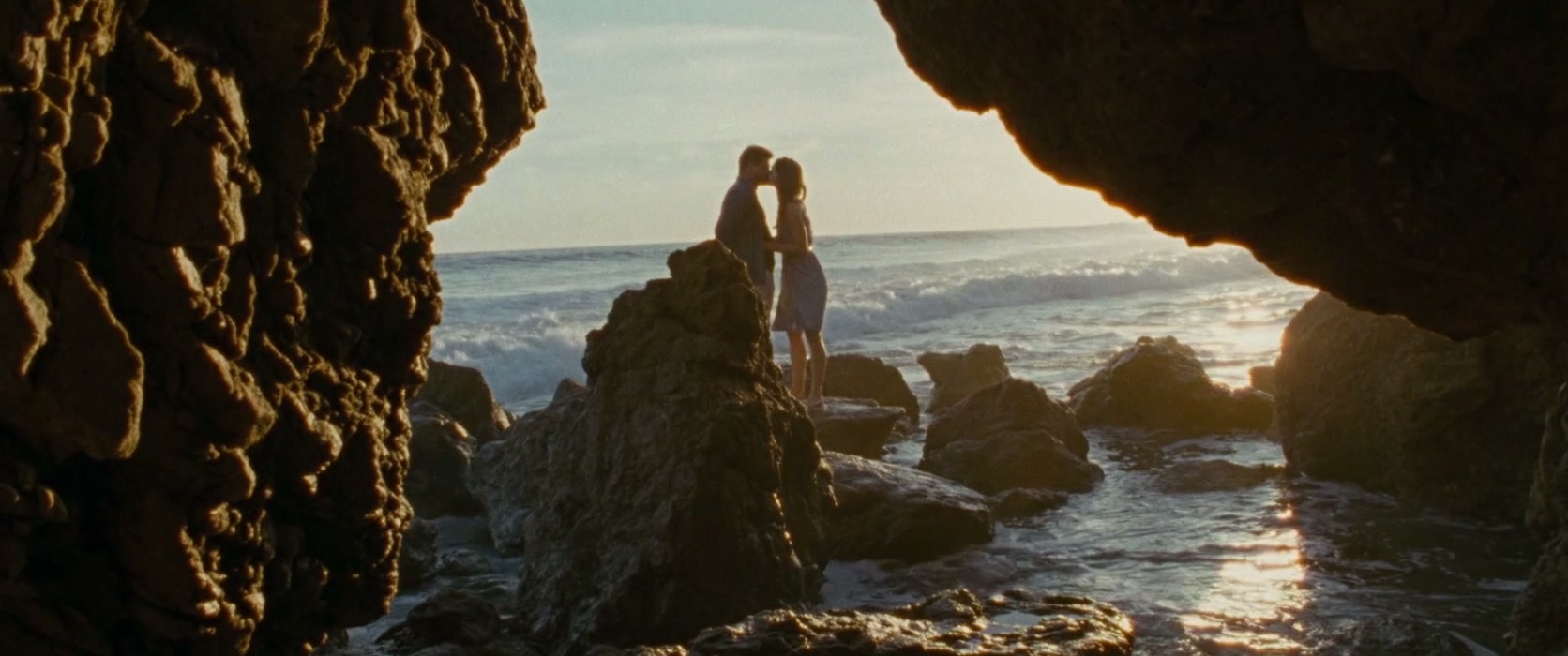 Una pareja se encuentra entre rocas junto al océano