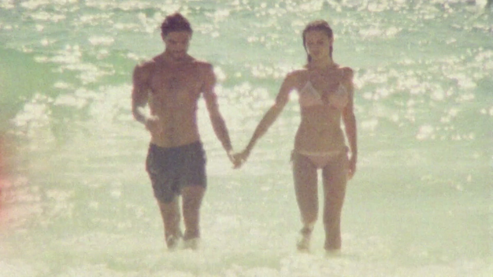 Una pareja sale del océano de la mano